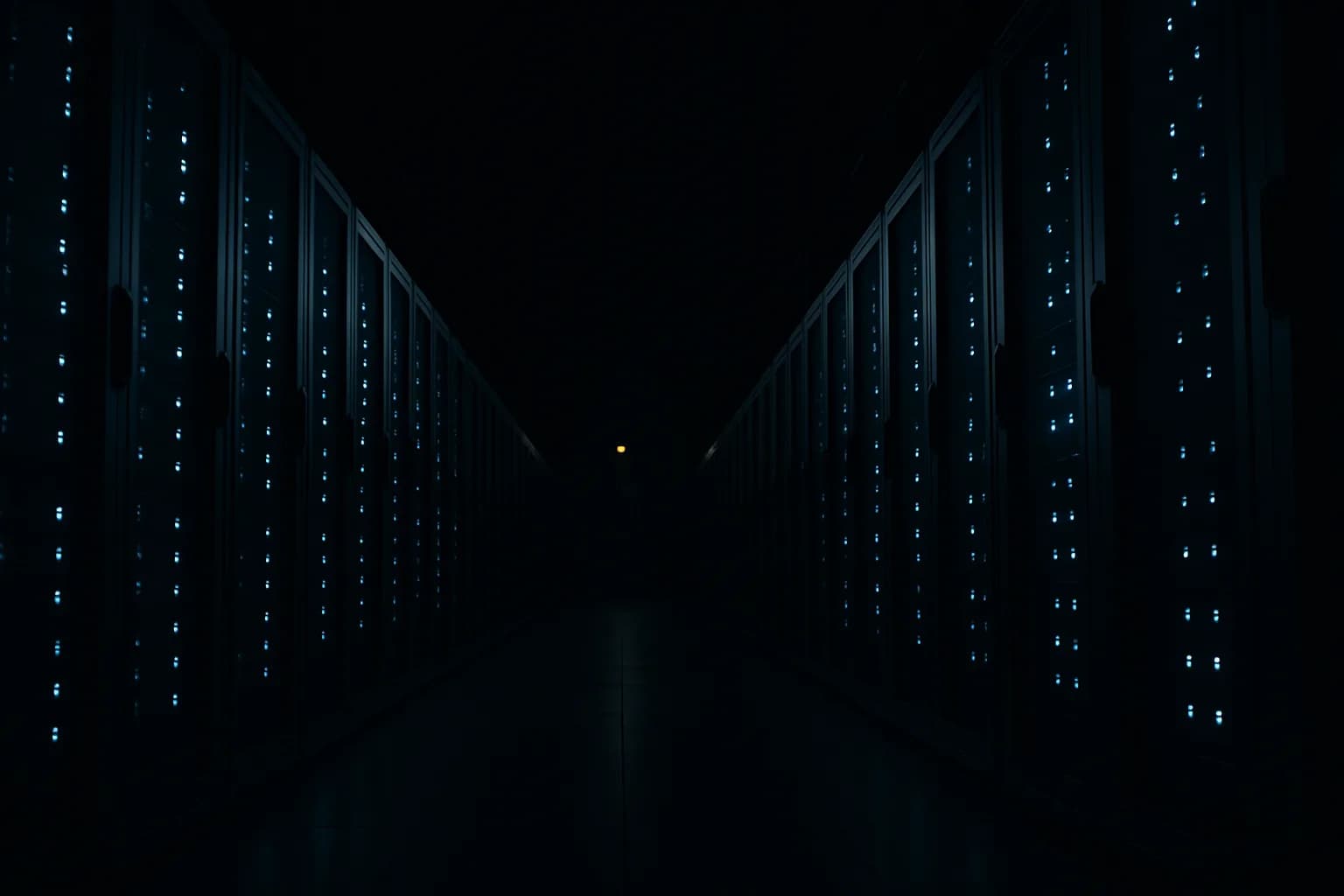 Server rack corridor in a dark data center, lit by pale blue and amber indicator LEDs