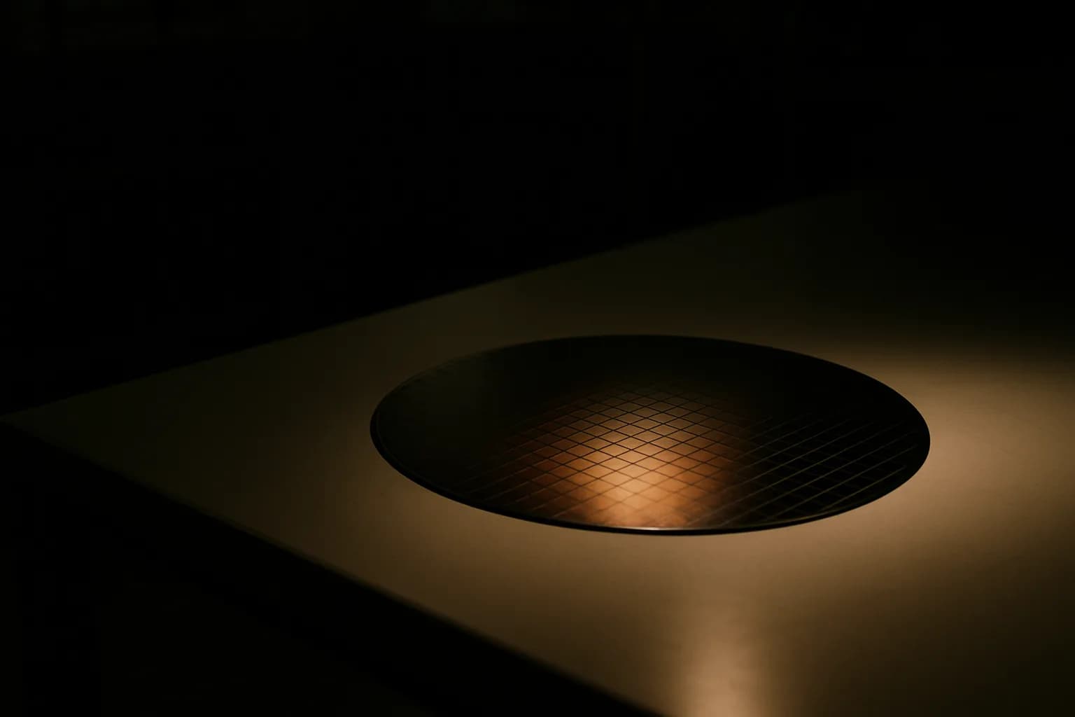 Bare silicon wafer on cleanroom inspection table with die grid visible under oblique light